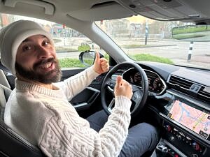 Geslaagde leerling met duim omhoog achter het stuur van de lesauto